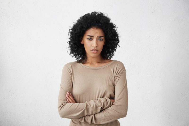 Indoor shot of skeptical young mixed race woman feeling suspicious, her look expressing disapproval or doubt, keeping arms crossed while having a suspicion that her husband cheated on her. horizontal Free Photo