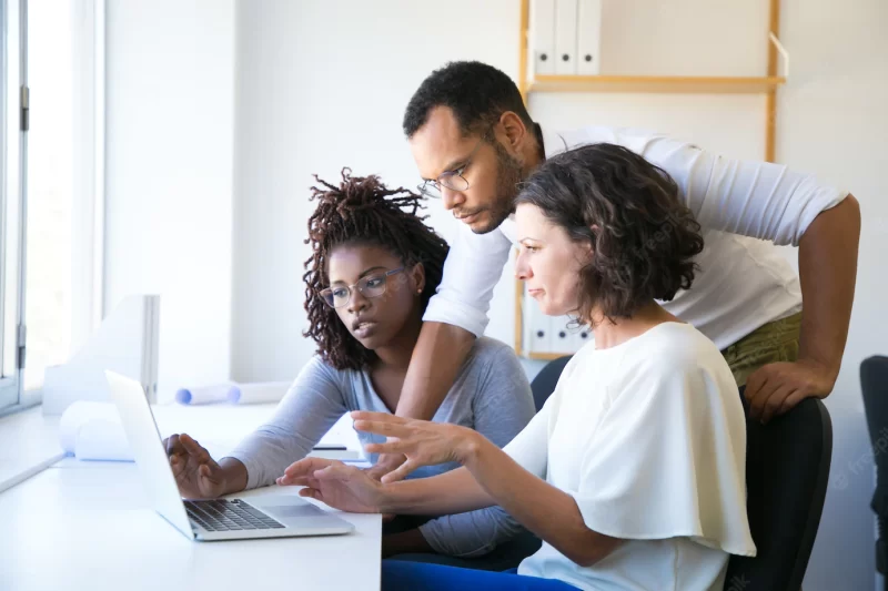 Instructor helping new employees with corporate software Free Photo