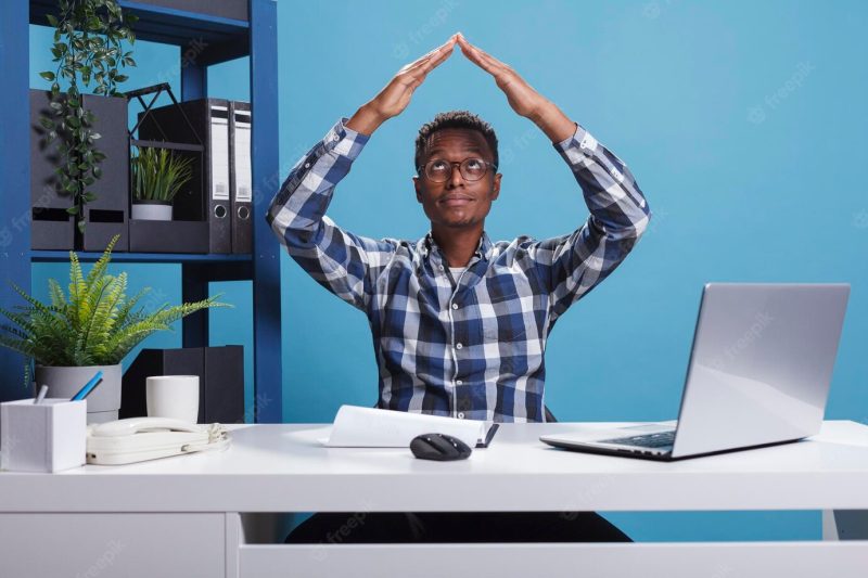 Insurance agency employee doing roof gesture with arms while feeling safe and secure indoor. company businessman advertising safety symbol while wishing for home protection. Free Photo