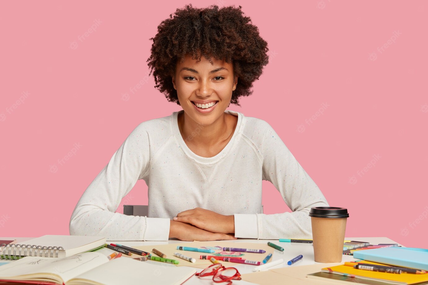 Isolated Shot Hilarious Dark Skinned Woman Has Afro Haircut Dressed Casual White Jumper Sits Desktop With Creative Chaos Drinks Takeaway Coffee Uses Crayons Has Toothy Smile Face 273609 29530