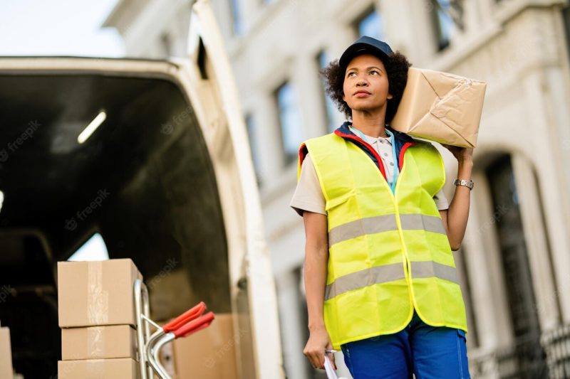 Low angle view of african american deliverer carrying a package in the city Free Photo