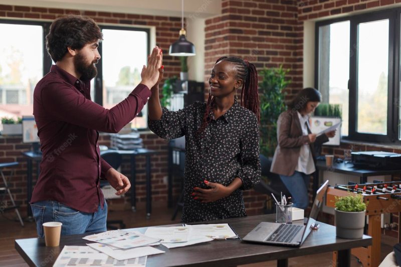 Marketing company employees congratulating each other for great startup marketing strategy results. happy smiling pregnant woman high fiving coworker for amazing presentation ideas. Free Photo