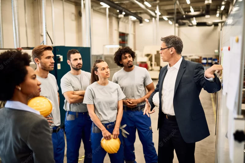 Mid adult businessman giving presentation to group of industrial workers in a factory Free Photo