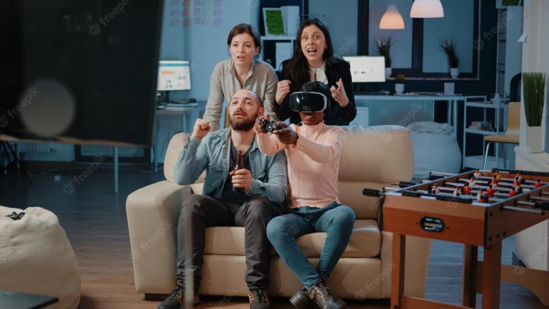 Multi ethnic people cheering while woman winning game with vr glasses and controller on tv console. workmates enjoying video games with joystick to have fun with activity after work Free Photo