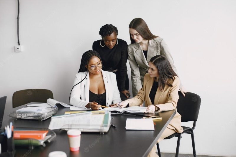 Multiracial office workers girls working together sitting at desk. discussing business project Free Photo