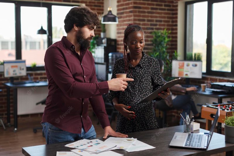 Office worker pointing out wrong accounting data while expectant mother having a clipboard in hand. marketing company employees reviewing profitable strategy ideas and project startup partners. Free Photo