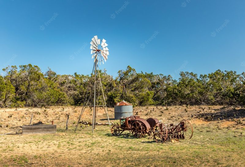 Old rusty tractor and a windmill on the back roads of Texas Free Photo