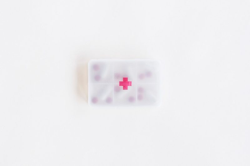 Overhead view of plastic pills container with first aid sign Free Photo