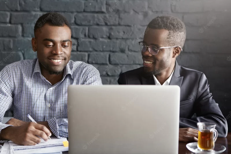 People, business, teamwork and cooperation concept. two african american corporate workers in formal clothing working together on common presentation on generic laptop computer in modern office Free Photo