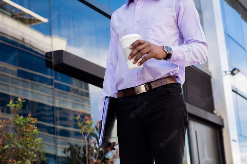 Portrait of afro businessman taking a break from work and drinking a cup of coffee outdoors. business concept. Free Photo