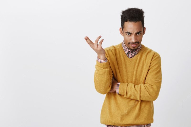 Portrait of annoyed good-looking male with afro haircut in yellow clothes, gesturing, expressing confusion, frowning, being displeased and questioned while hearing accusation Free Photo