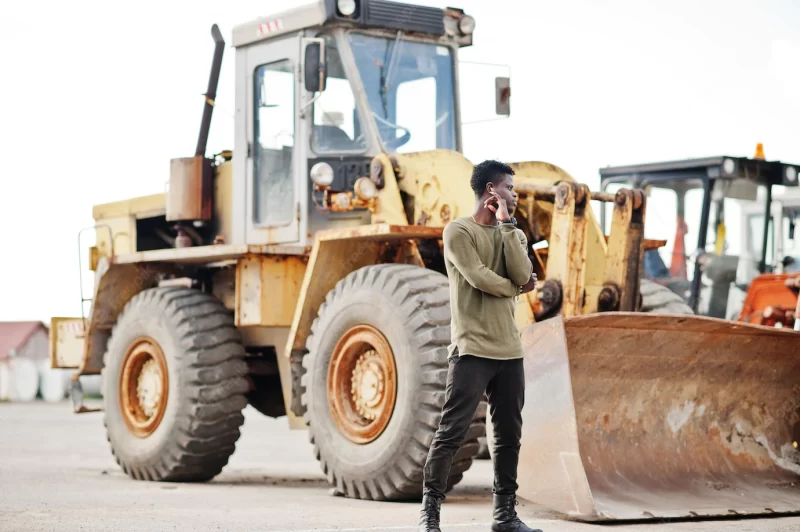 Portrait of an attractive black african american man posing next to the industrial machinery Free Photo