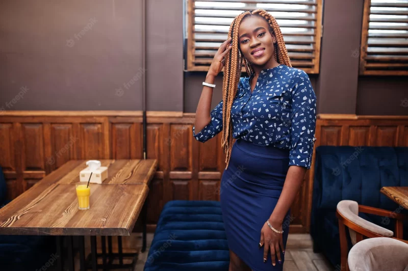 Portrait of beautiful young african business woman with dreadlocks wearing  blue blouse and skirt posed in cafe Free Photo