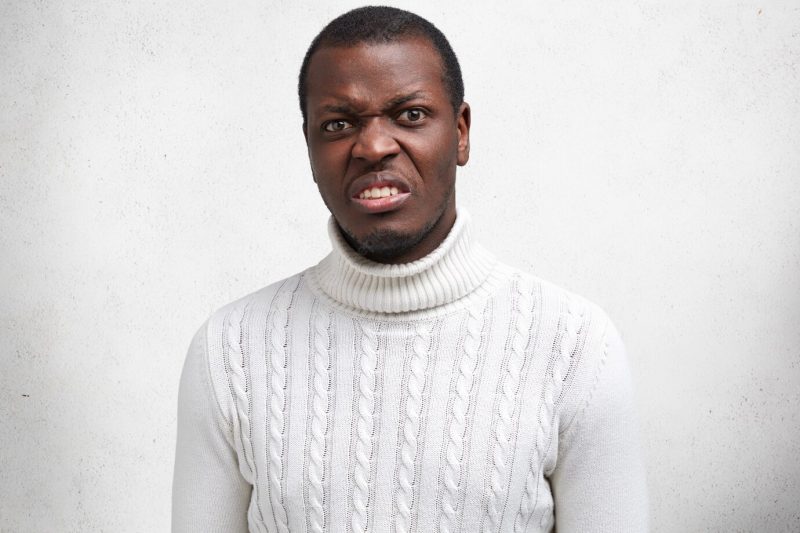 Portrait of displeased handsome young African American male has disgusting expression, frowns face, expresses negativity, dressed in casual sweater. Free Photo