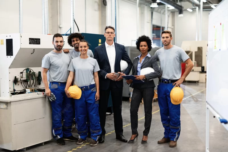 Portrait of group of engineers and corporate managers standing in a factory and looking at camera Free Photo