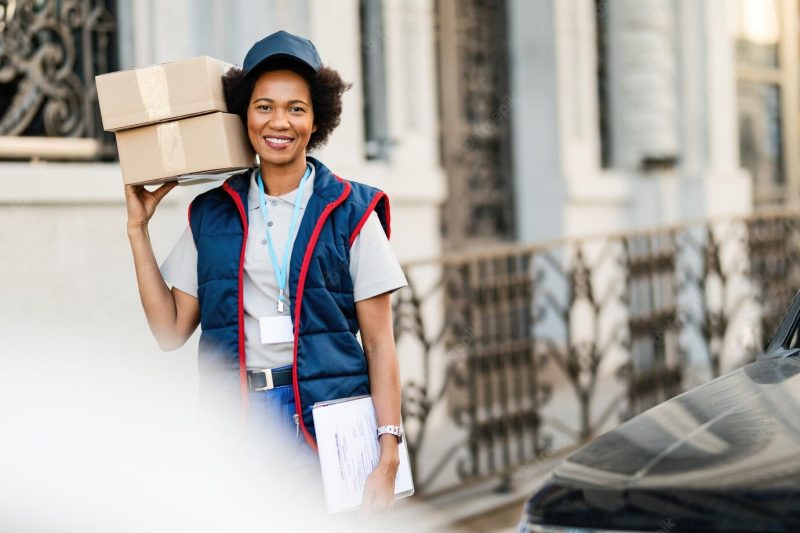 Portrait of happy African American courier carrying packages while making a delivery in the city Free Photo