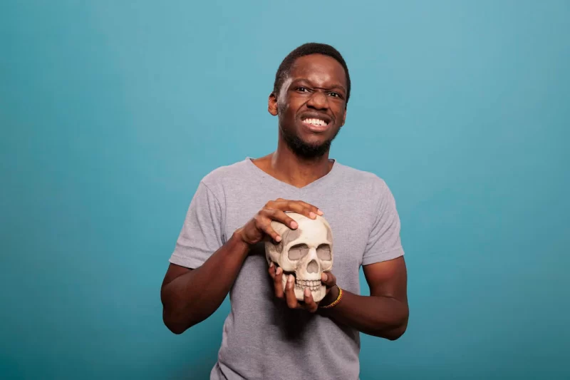 Portrait of male model holding skull from human skeleton to study genetic scientific brain disease, anatomy and biology education. anatomical subject to discover science knowledge. Free Photo