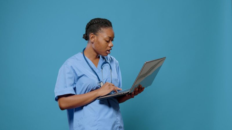 Portrait of medical nurse in uniform looking at laptop display to work on healthcare system and practice medicine. woman assistant with stethoscope using computer to have expertise. Free Photo