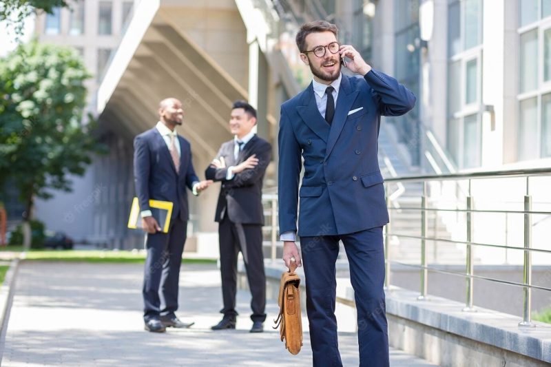 Portrait of multi ethnic business team.three men standing against the background of city. the foreground of a european man talking on the phone. other men is Chinese and African-American. Free Photo