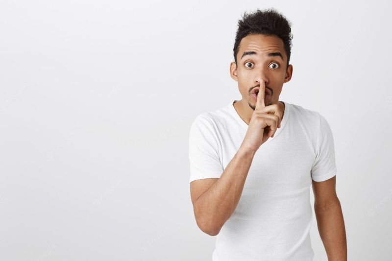 Portrait of young African-American guy asking keep quiet, shushing, don’t talk gesture Free Photo