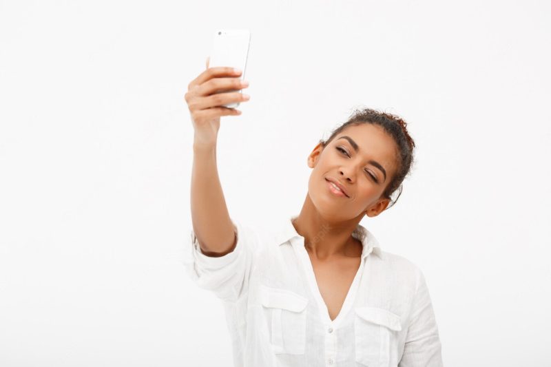 Portrait of young frican woman making selfie on white background Free Photo