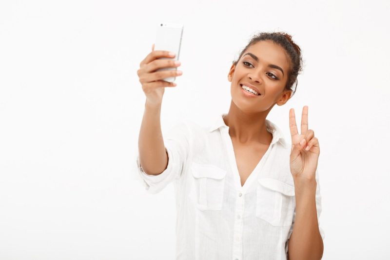 Portrait of young African woman making selfie on white Free Photo