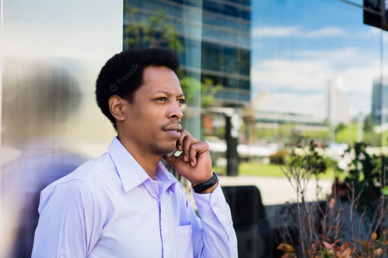 Portrait of young afro businessman talking on mobile phone outdoors at the street. business concept. Free Photo