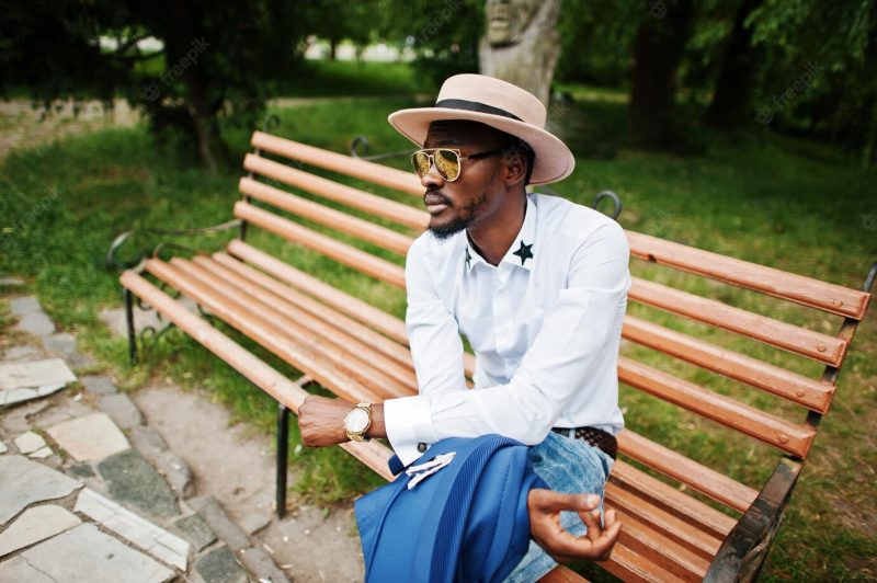 Rich black man sitting on bench at golden sunglasses and hat Free Photo