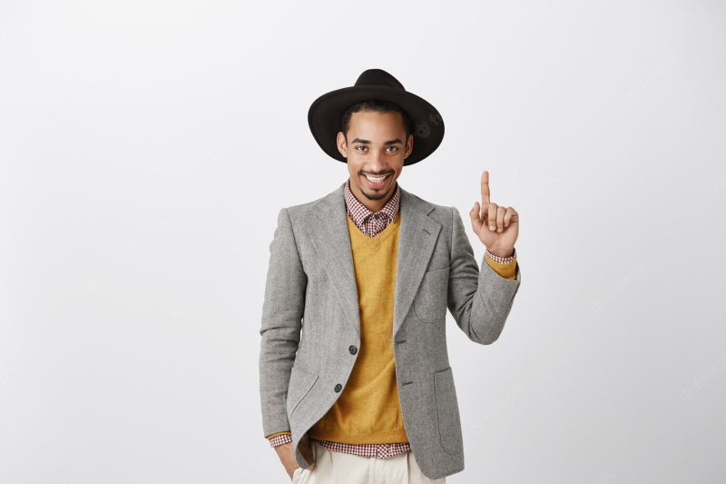 Sassy handsome African American businessman in suit pointing finger up, showing number one Free Photo