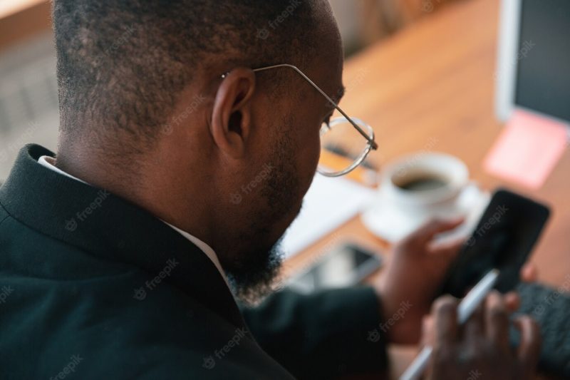 Surfing online. African-American entrepreneur, businessman working concentrated in office. Looks serious and busy, wearing classic suit, jacket. concept of work, finance, business, success, leadership. Free Photo