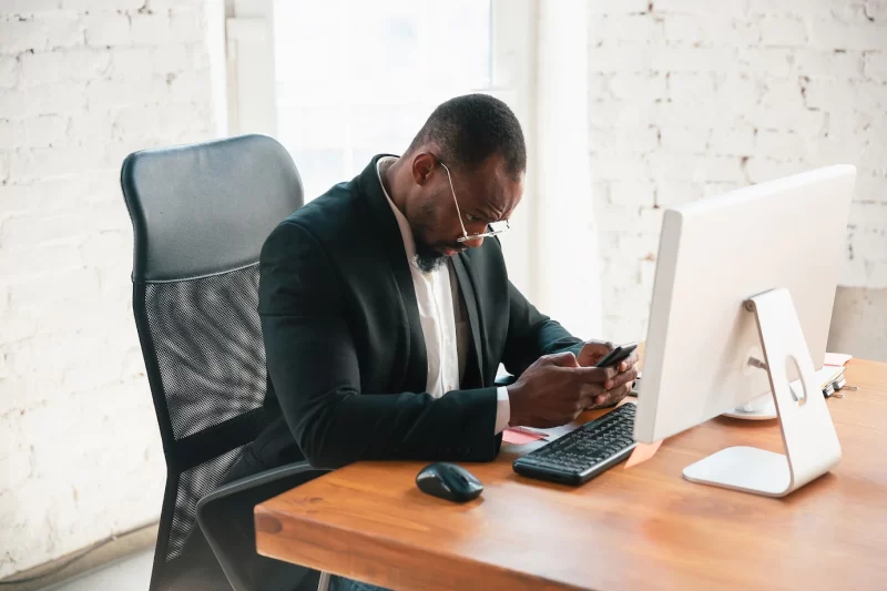 Serfing online. african-american entrepreneur, businessman working concentrated in office. looks serios and busy, wearing classic suit, jacket. concept of work, finance, business, success, leadership. Free Photo