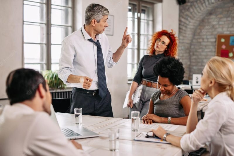 Serious businessman explaining something to his coworkers during a meeting at the office Free Photo