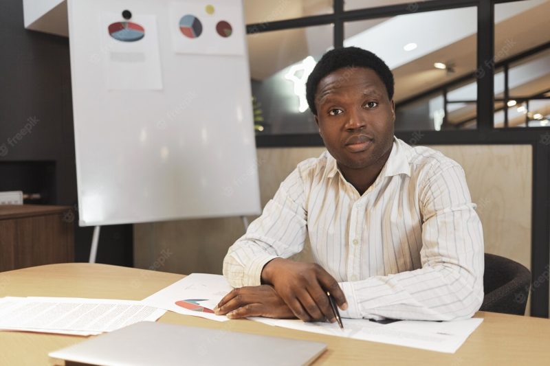 Serious confident african ceo wearing formal striped shirt sitting at conference room Free Photo