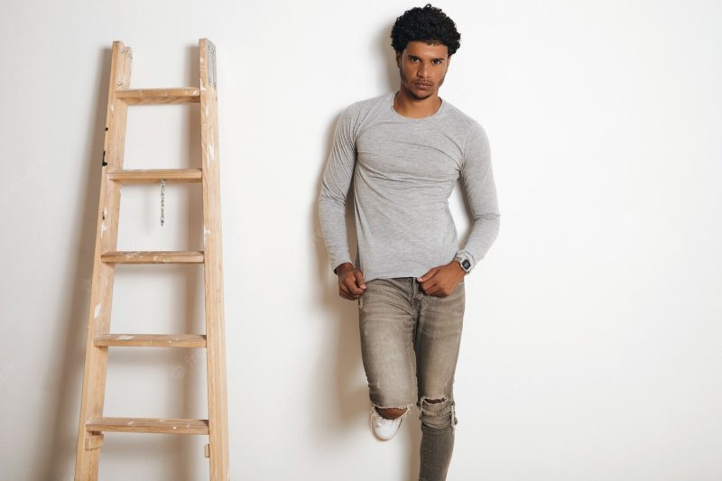 Serious latino man wears blank grey longsleeve and poses near ladder , isolated on white Free Photo