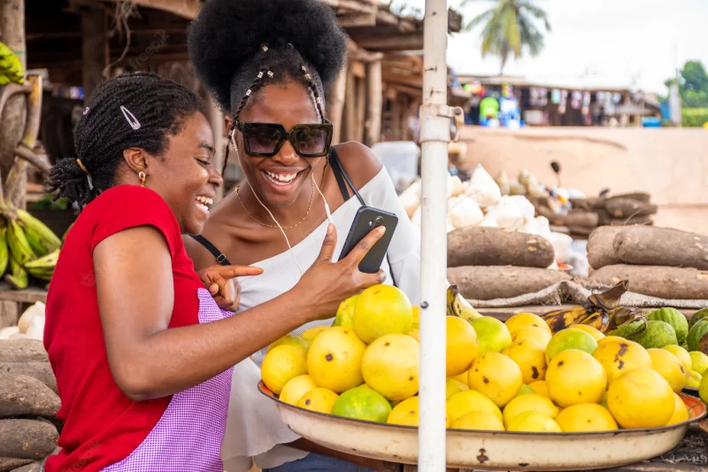 Shallow focus of an african female seller showing content in a phone to a customer at a market Free Photo