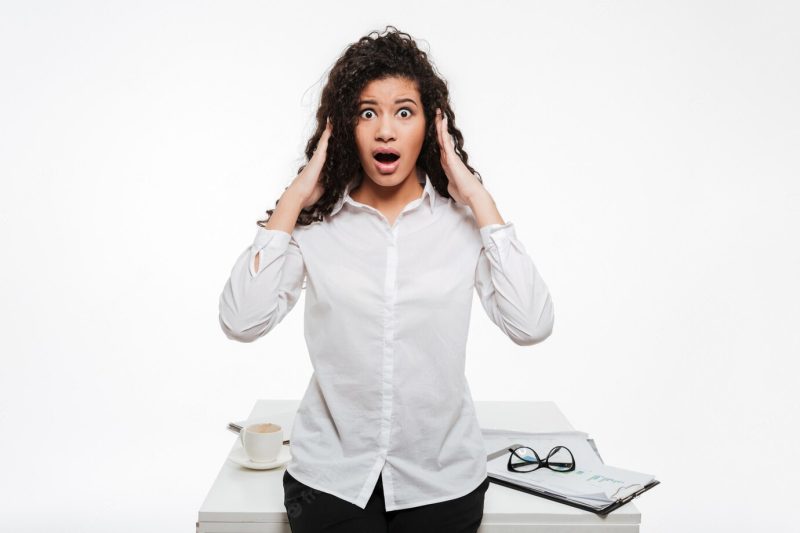 Shocked African business lady standing near table Free Photo