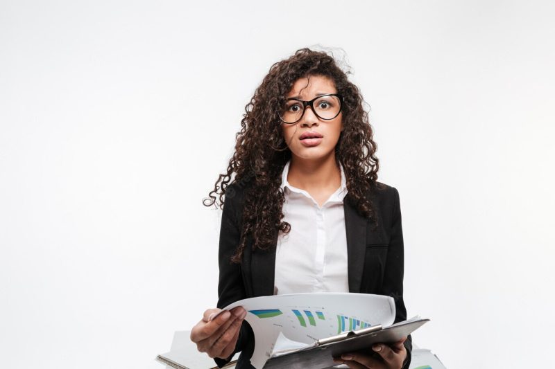 Shocked African business lady wearing glasses reading gazette Free Photo