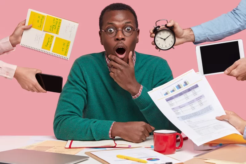 Shot of surprised scared black man looks with terrified expression, wears round spectacles, studies documents with graphics and charts Free Photo