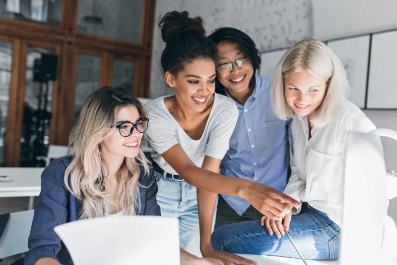 Smiling black girl spending time in office, joking with colleagues Free Photo