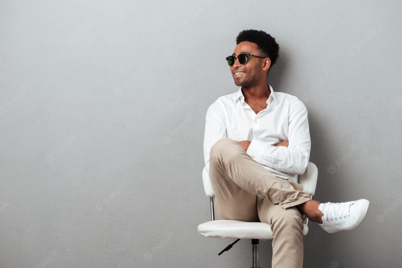 Smiling happy African man posing in a chair Free Photo