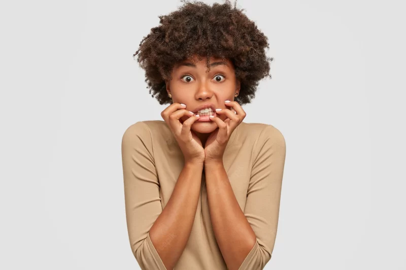 Stressful emotive young woman keeps hands near mouth Free Photo