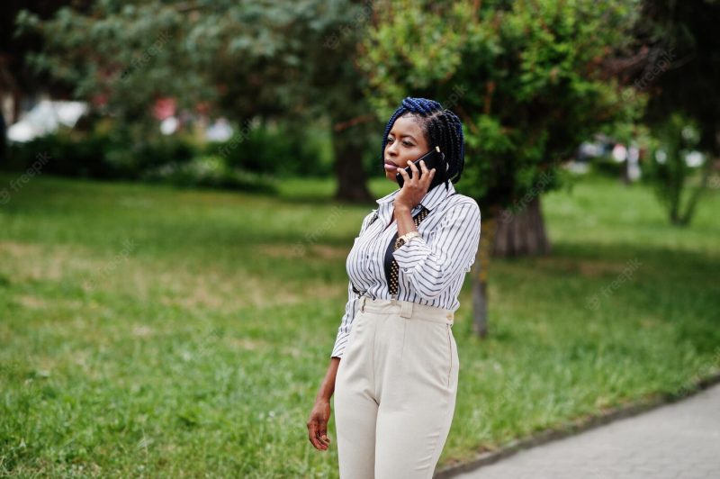 Stylish african american business woman at trousers with suspender and blouse posed outdoor and speaking on mobile phone Free Photo