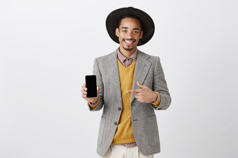 Stylish African American businessman pointing finger at smartphone screen, showing application Free Photo