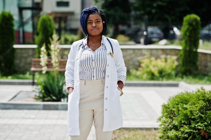 Stylish african american doctor with stethoscope and lab coat posed at backyard of hospital Free Photo