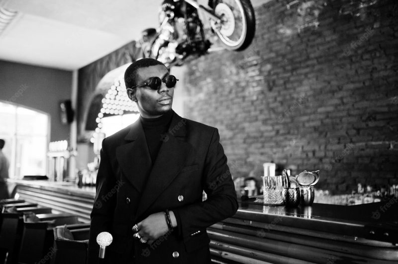 Stylish african american gentleman in elegant black jacket and sunglasses holding retro walking stick as cane flask or tippling cane with golden diamond ball handle rich fashionable afro man Free Photo