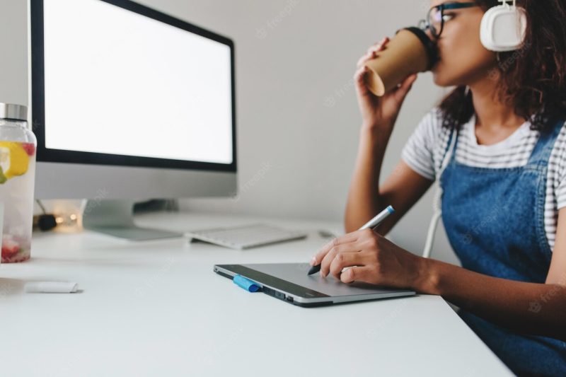 Stylish black girl in glasses drinking coffee with pleasure while using tablet Free Photo