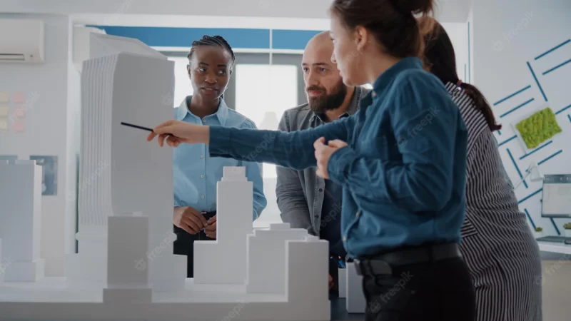 Team of architects analyzing building model to plan construction layout and blueprints on paper. architectural people working with maquette to design structure and project development. Free Photo