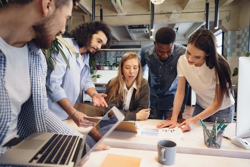 Team of diverse coworkers in modern office discuss their project together Free Photo