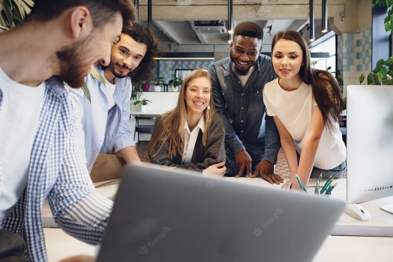 Team of diverse coworkers in modern office discuss their project together Free Photo