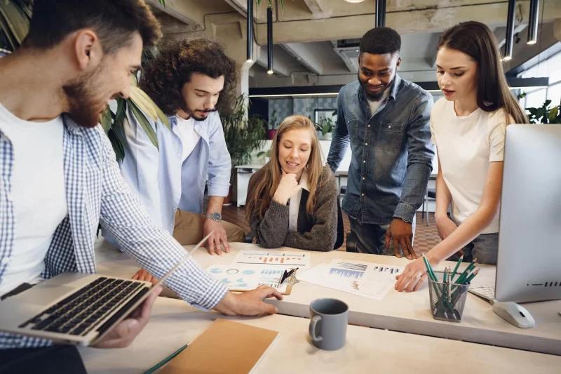 Team of diverse coworkers in modern office discuss their project together Free Photo